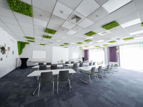 a conference room with tables and chairs and a screen at Ibis Styles Linz in Linz