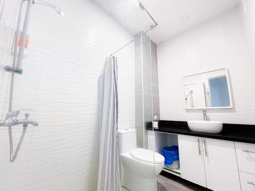 a white bathroom with a toilet and a sink at CARIBBEAN Studios LOS CORALES BEACH WIFI POOL & SPA in Punta Cana