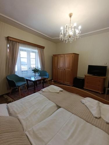 a bedroom with two beds and a table and a chandelier at Hotel Salamander - Garni in Banská Štiavnica