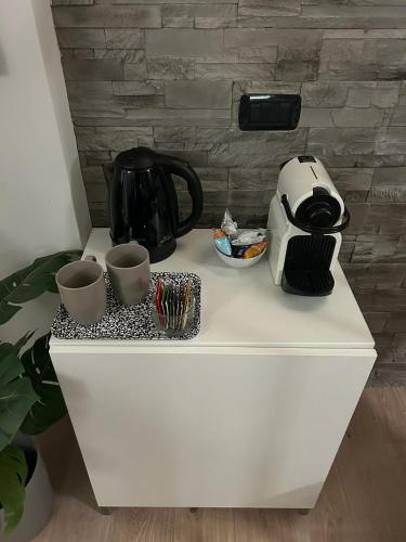 a white counter with two cups and a tea kettle at Nest Porta Milano in Tribiano