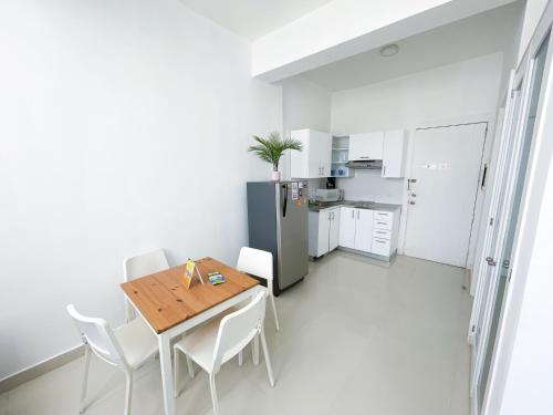 a white kitchen with a wooden table and white chairs at CARIBBEAN Studios LOS CORALES BEACH WIFI POOL & SPA in Punta Cana