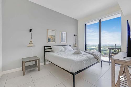 a white bedroom with a bed and a balcony at DTW Doral 2BD Condo Skyline Views in Miami