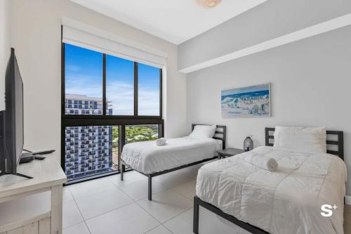 a bedroom with two beds and a tv and a window at DTW Doral 2BD Condo Skyline Views in Miami