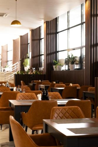 Un comedor con mesas y sillas y ventanas. en Hotel Amelia Mare, en Golem