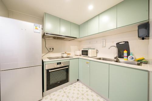 a kitchen with white cabinets and a sink and a microwave at Tonight Homestay West Nanjing Road Branch Shanghai in Shanghai