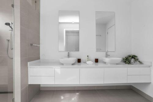 un bagno bianco con due lavandini e uno specchio di Sunrise Serenity - modern luxury a Apollo Bay