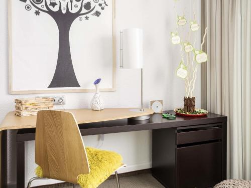 a desk with a chair and a table with a lamp at Novotel Warszawa Airport in Warsaw