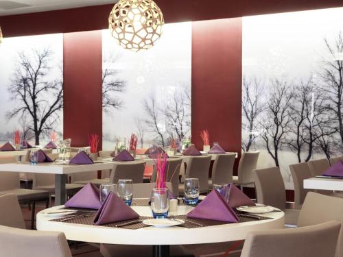 a dining room with tables and chairs with purple napkins at Novotel Warszawa Airport in Warsaw