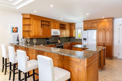 a kitchen with wooden cabinets and white bar stools at 2 Bdrm Stunning Marina View at The Yacht Club C5 in Providenciales