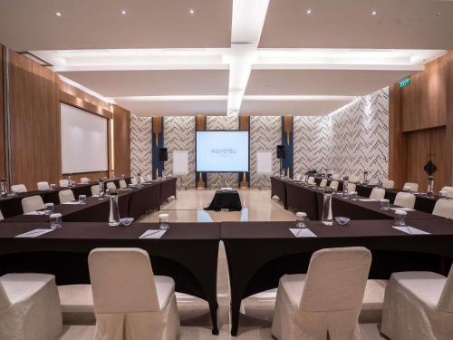 a conference room with a table and chairs and a screen at Novotel Bogor Golf Resort in Bogor