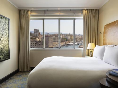 a hotel room with a large bed and a large window at Sofitel Marseille Vieux-Port in Marseille