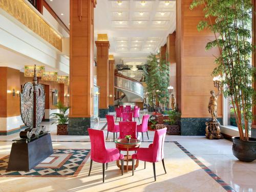 a restaurant with pink chairs and tables in a lobby at Novotel Solo in Solo