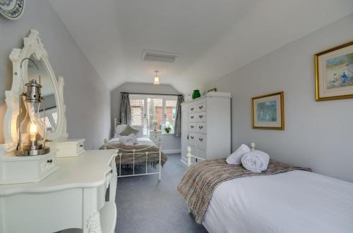 een slaapkamer met twee bedden, een bureau en een spiegel bij Garden Cottage in Holt