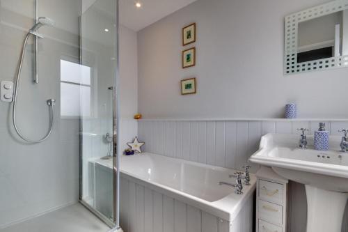 een witte badkamer met douche en wastafel bij Garden Cottage in Holt