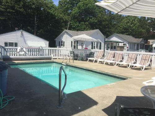 uma piscina com espreguiçadeiras e uma casa em Crosswinds Motel em Old Orchard Beach