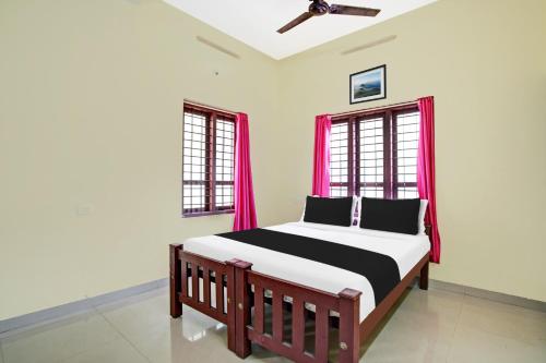 Un dormitorio con una cama y dos ventanas. en Hotel O Nakshathra Inn, en Kazhakuttam