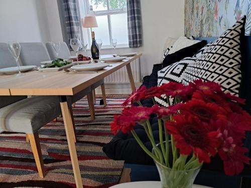 a dining room with a table and red flowers at All Saints Crescent in Westbury
