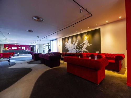 a living room with red couches and a painting on the wall at Mercure Bordeaux Lac in Bordeaux