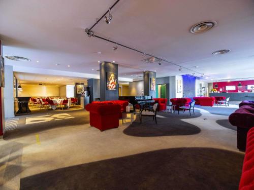 a large room with red chairs and tables in it at Mercure Bordeaux Lac in Bordeaux