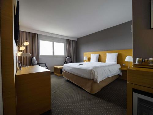 a hotel room with a bed and a television at Mercure Bordeaux Lac in Bordeaux