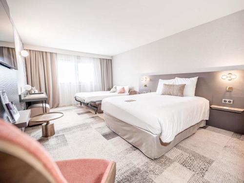 a hotel room with two beds and a television at Mercure Bordeaux Lac in Bordeaux
