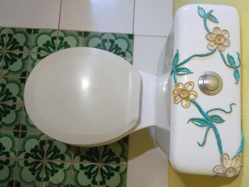 a white toilet with flowers painted on the side of it at Hospedaria das Marias no Vale do Capão in Vale do Capao
