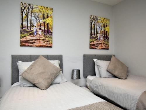 two beds in a bedroom with two paintings on the wall at 4 Bed in Oswestry 75175 in Kinnerley