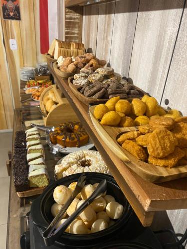 a buffet of different types of bread and pastries at Pousada Vila do Cowboy in Penha