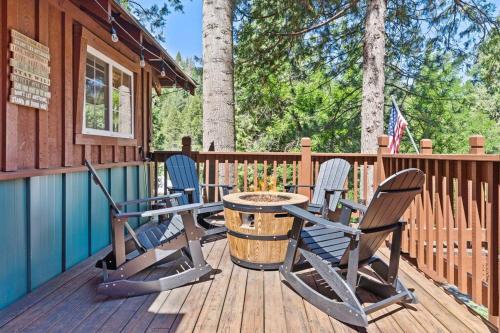 a deck with chairs and a table on a cabin at Sugar Pine cabin in the woods King bed Fire pit in Oakhurst