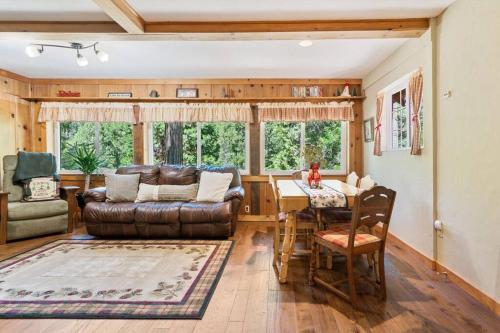a living room with a leather couch and a table at Sugar Pine cabin in the woods King bed Fire pit in Oakhurst