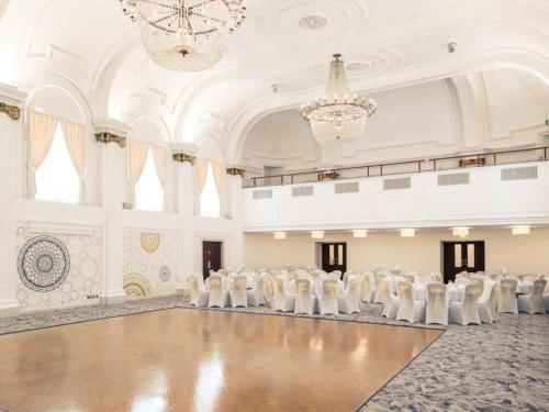 a ballroom with white chairs and a chandelier at The Grand Bristol City Center By Dancenter in Bristol