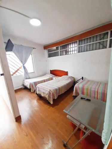 a room with two beds and a table in it at Hostal Pampaloja Antof in Antofagasta