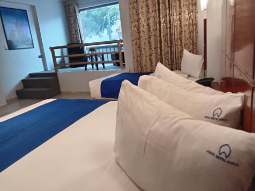 a bed with white pillows in a room at Aqua Hotel Cusco in Cusco