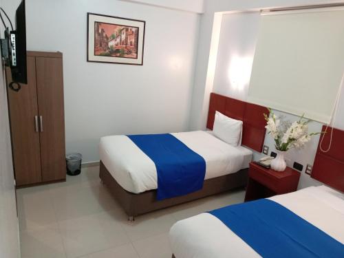 a hotel room with two beds with blue and white sheets at Aqua Hotel Cusco in Cusco