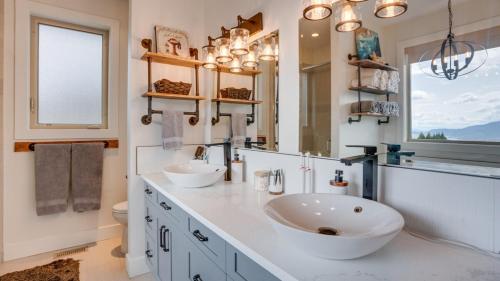 a bathroom with two sinks and a large mirror at Hot Tub, Pool, City Views, close to Silver Star in Vernon