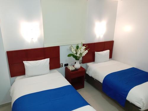 a room with two beds and a vase of flowers at Aqua Hotel Cusco in Cusco