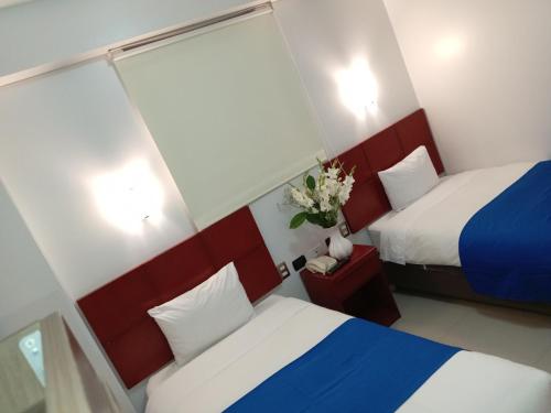 a hotel room with two beds and a vase of flowers at Aqua Hotel Cusco in Cusco