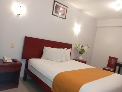 a bedroom with a bed and a phone in it at Aqua Hotel Cusco in Cusco