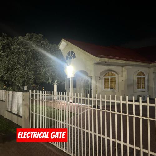 a white fence in front of a house with a light at Paramaribo Villa Near Vibrant District incl Kitchen Household Service in Paramaribo