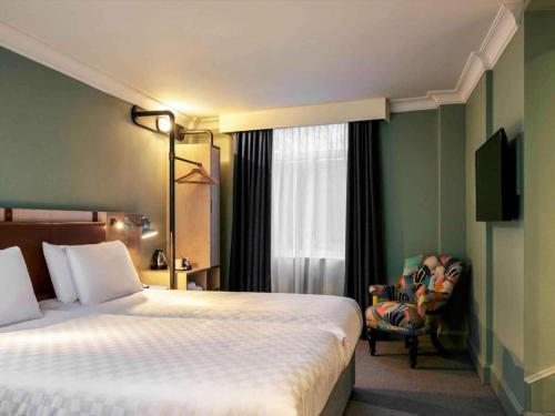 a hotel room with a bed and a chair at The Grand Bristol City Center By Dancenter in Bristol