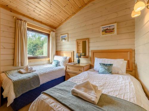 a bedroom with two beds in a log cabin at 3 Bed in Clovelly 85290 in Woolfardisworthy