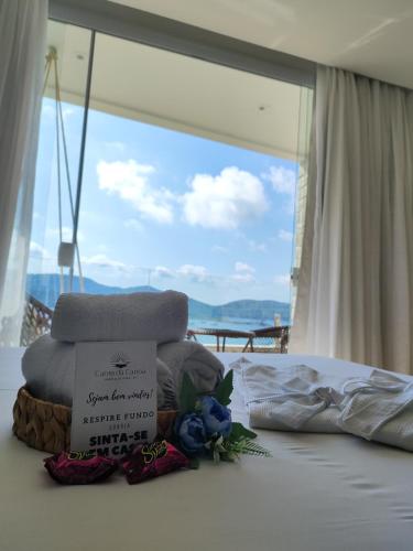 a pile of towels sitting on a bed with a window at Canto da Canoa in Arraial do Cabo