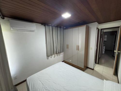 ein Schlafzimmer mit einem weißen Bett und einem Schrank in der Unterkunft Villa Hípica Resort Gravatá - Apartamento 701 in Gravatá
