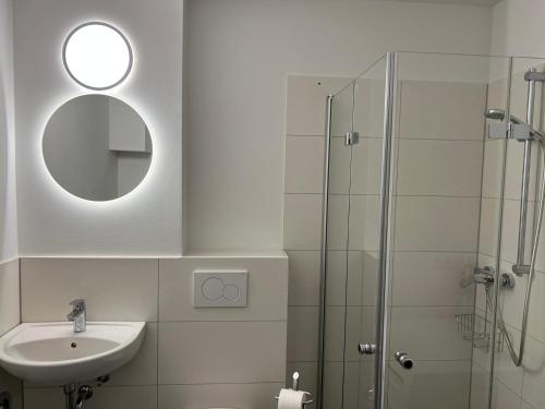 a bathroom with a sink and a shower with a mirror at NEU - Apartment in Brühl-City in Brühl