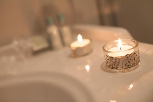 two candles sitting on top of a bathroom sink at B&B Palazzo Mantegna in Gioiosa Ionica