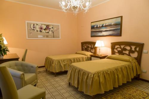 a room with two beds and a chair and a chandelier at B&B Palazzo Mantegna in Gioiosa Ionica