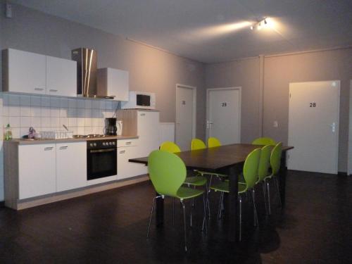 eine Küche mit einem Tisch und grünen Stühlen in der Unterkunft Bergedorf Haus 9 in Hamburg