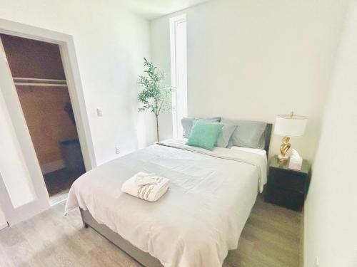 a white bedroom with a bed with towels on it at Newly Built Stylish Modern 2B In LA in North Sherman Way