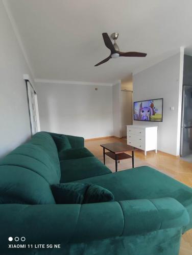 a green couch in a living room with a ceiling fan at Warsaw Shire in Warsaw