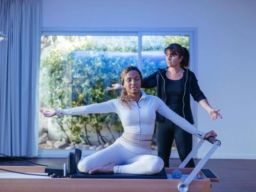 a woman sitting on a pilates reformer with another woman at Sofitel Quiberon Thalassa sea & spa in Quiberon